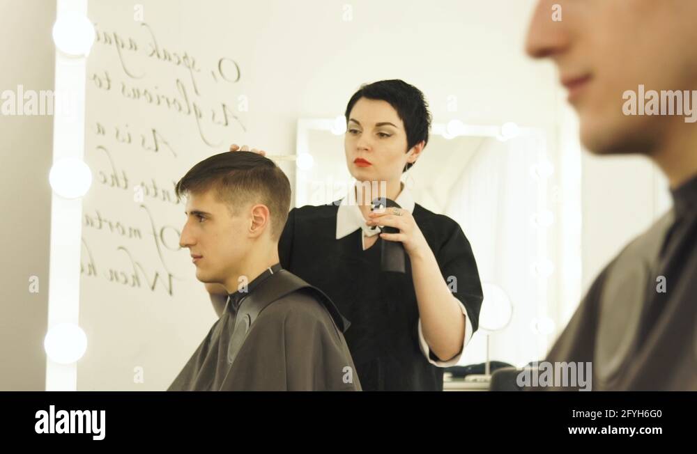 Hairdresser spraying water and combing wet hair before cutting. Male
