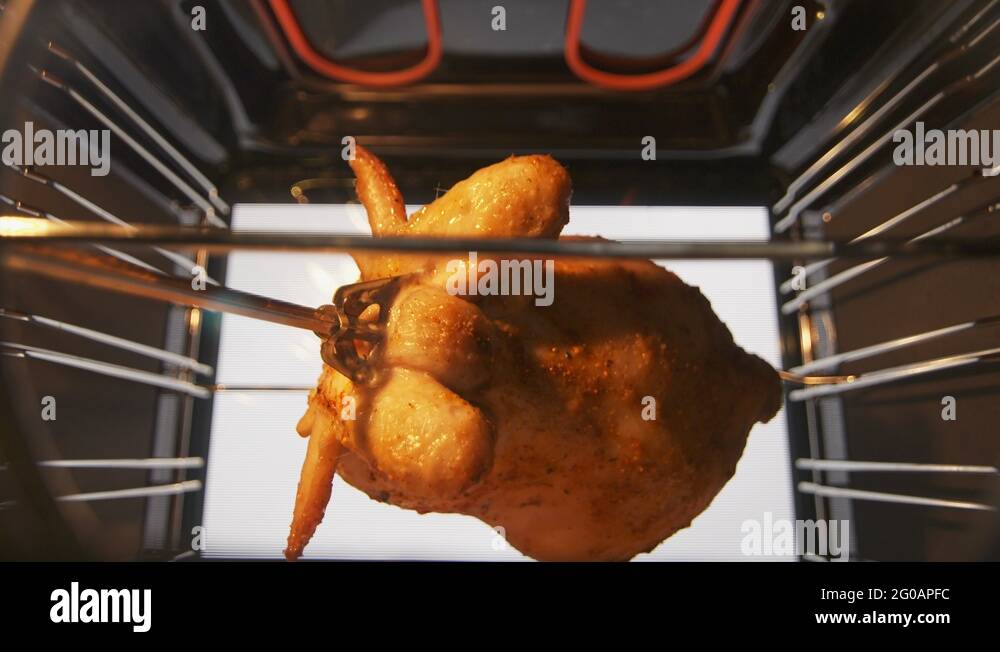 Cooking roasted whole chicken on the rotisserie spit in hot convection