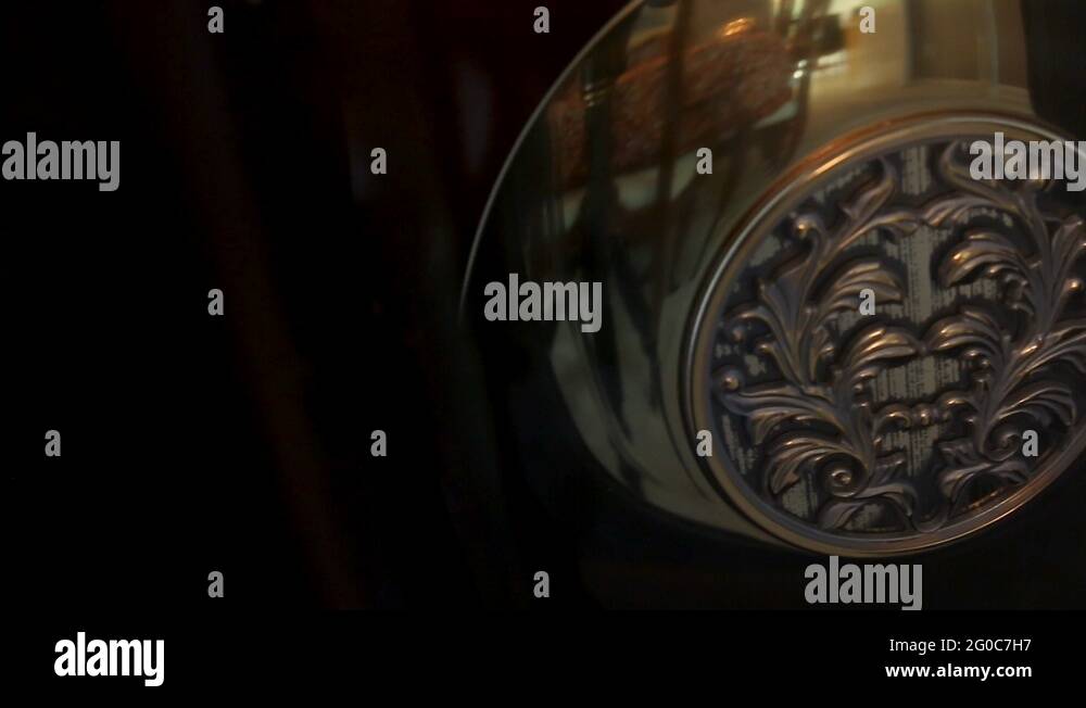 Decorative pendulum on a grandfather clock swinging back and forth