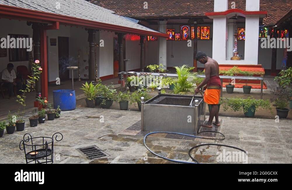 Laborer cleaning the altar of coconut breaking ritual at Hindu temple