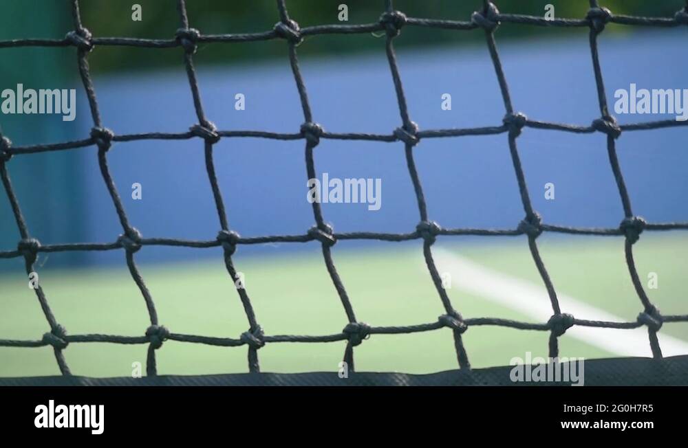 Tennis ball hits the grid falling on a tennis court. slow motion