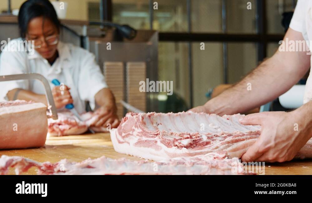 Bearded butcher cutting meat for sale at a butchers shop Stock Video