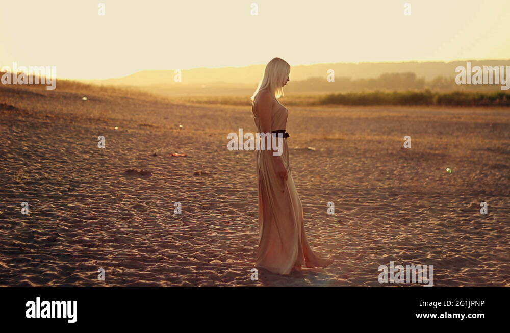 Young seductive woman with long hair in a beautiful dress walks on the ...