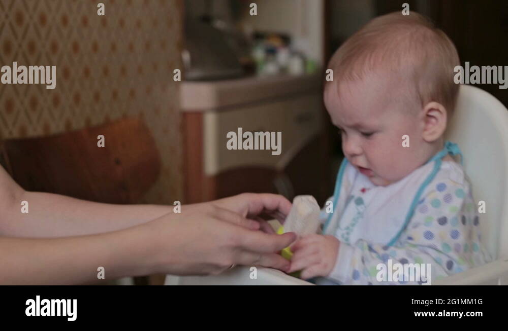 Mother give nibbler (food feeder) with the fruit for her son Stock