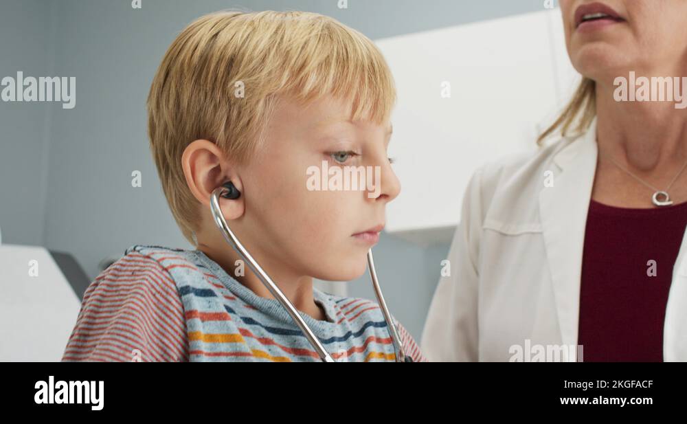 Little boy listening to his own heartbeat using stethoscope at