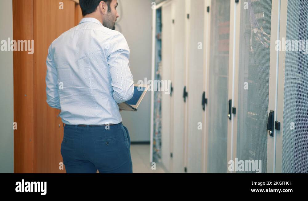 Man Working On Laptop In Server Room Checking Rack Server Cabinet And ...