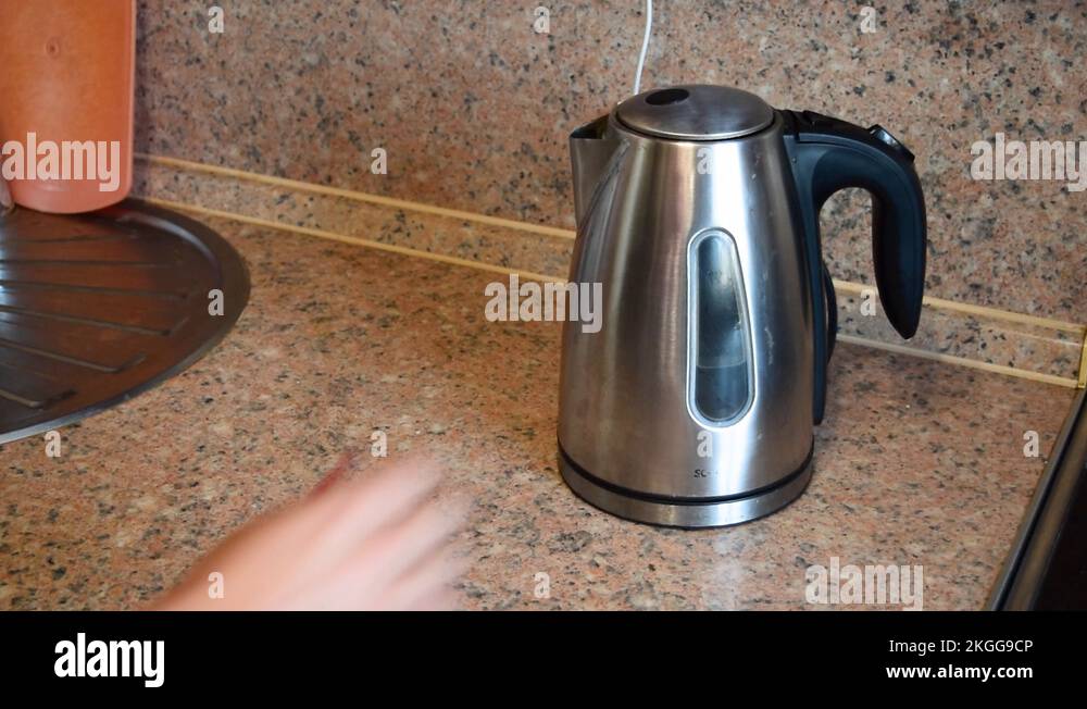 Close up of woman's hand turning on switch on electric kettle Stock