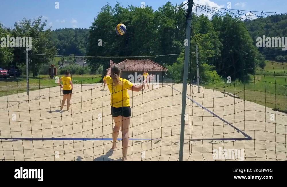 Players on the other side of a volleyball court are blocking and
