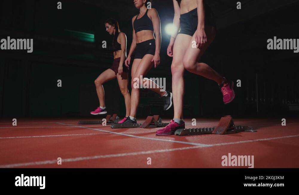 Female runners at athletics track crouching at the starting blocks ...
