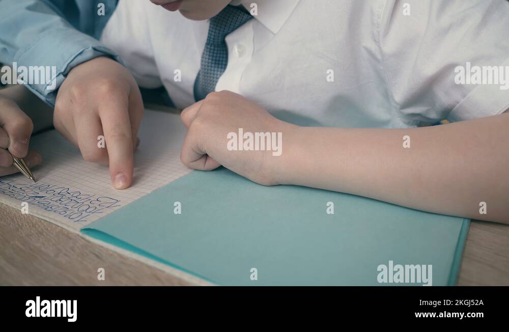Schoolchildren do homework, write numbers in notebook, helping each ...