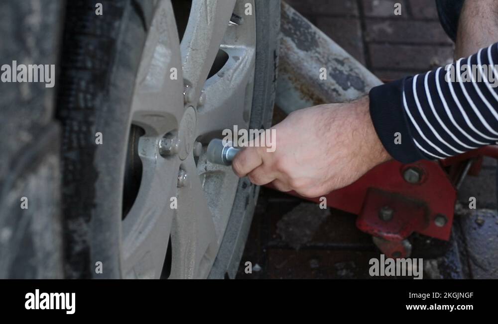 Man Unscrew the nuts to remove and change the wheel of a car Stock