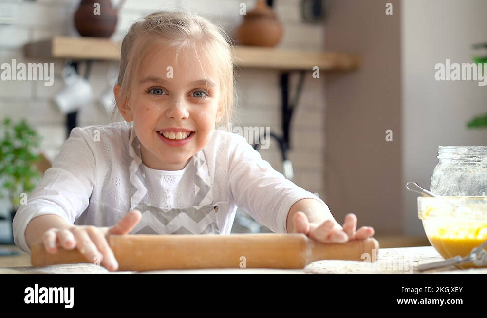 Close up portrait of cute little kid girl kneading dough using rollin
