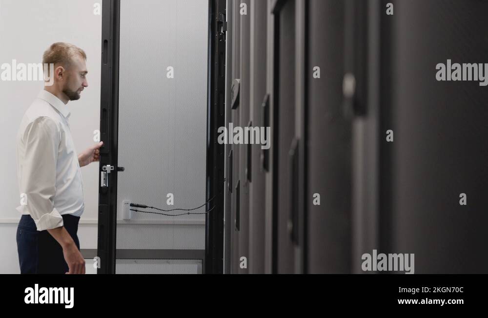 Man open server rack and typing at laptop in datacenter room Stock ...