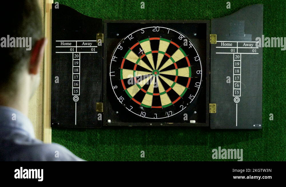Man throwing a dart arrow in target center of dartboard in game of darts. 4K Stock Video Footage