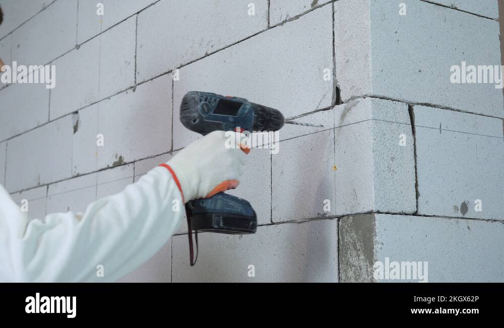 builder drilling holes in block wall and inserting dowels Stock Video