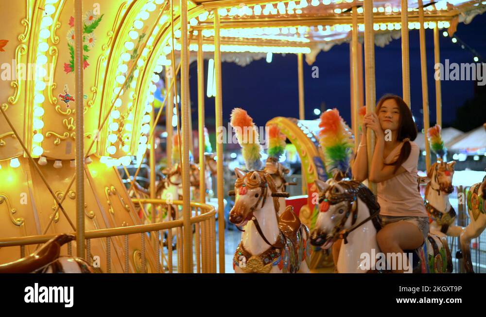 Teenager beautiful asian woman rides carousel in amusement park ...