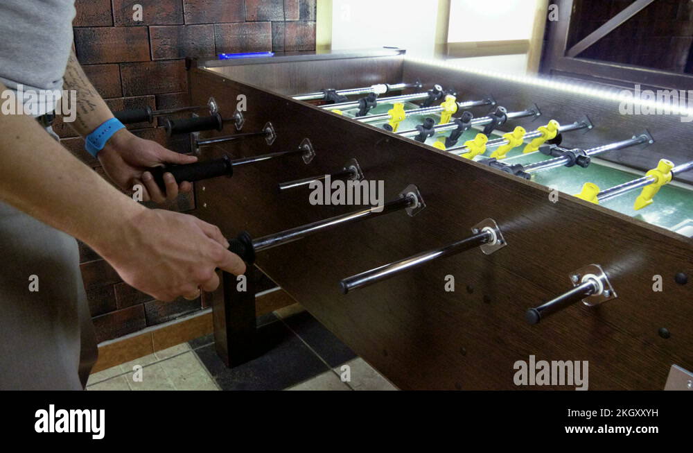 Foosball. Two men playing a table football, kicker with miniature