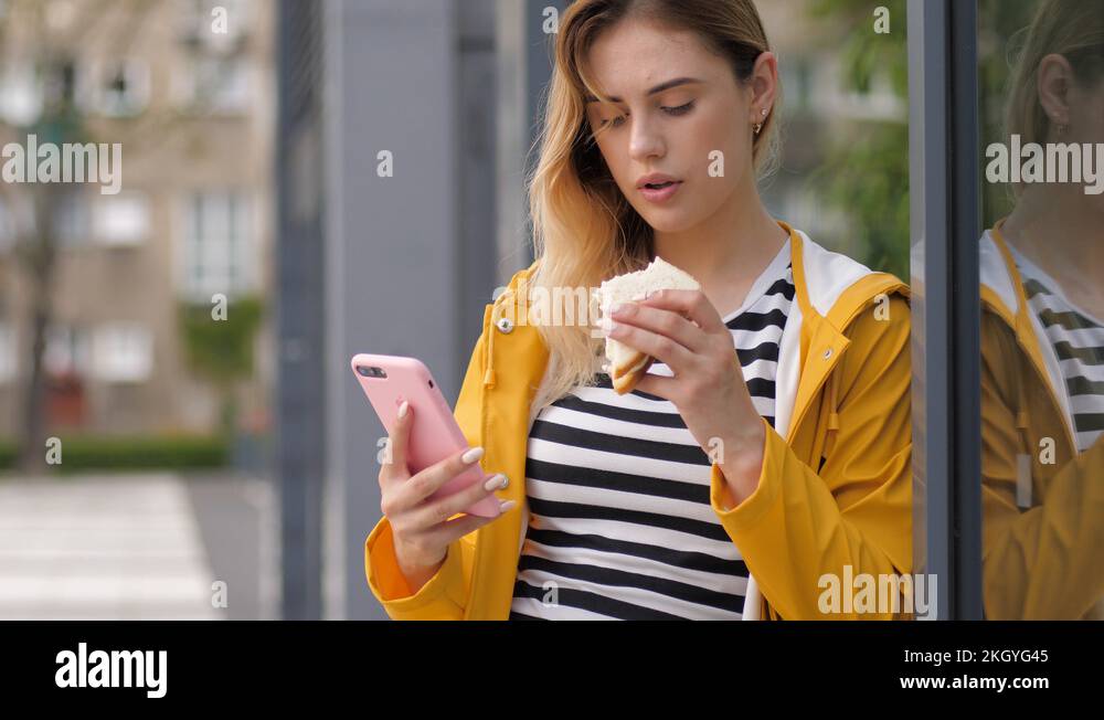 Eating sandwich young cute girl stay using mobile smartphone social media typing Stock Video