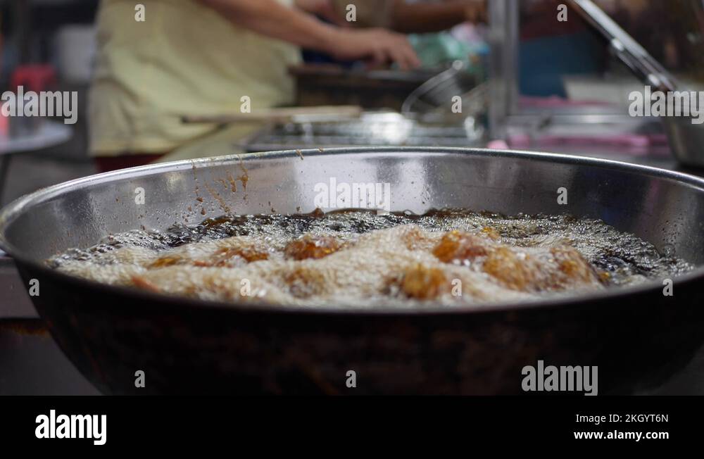 Breaded chicken cooking in a deep fryer full of hot, bubbling vegetable