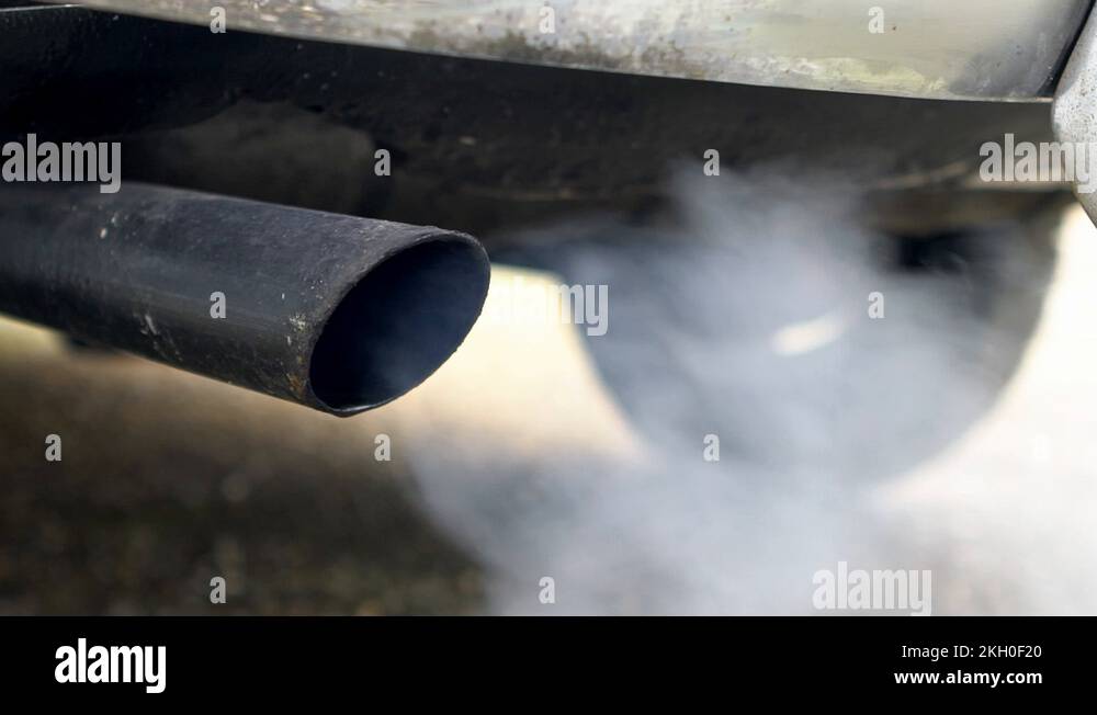 Closeup combustion fumes coming out of car exhaust pipe which strongly