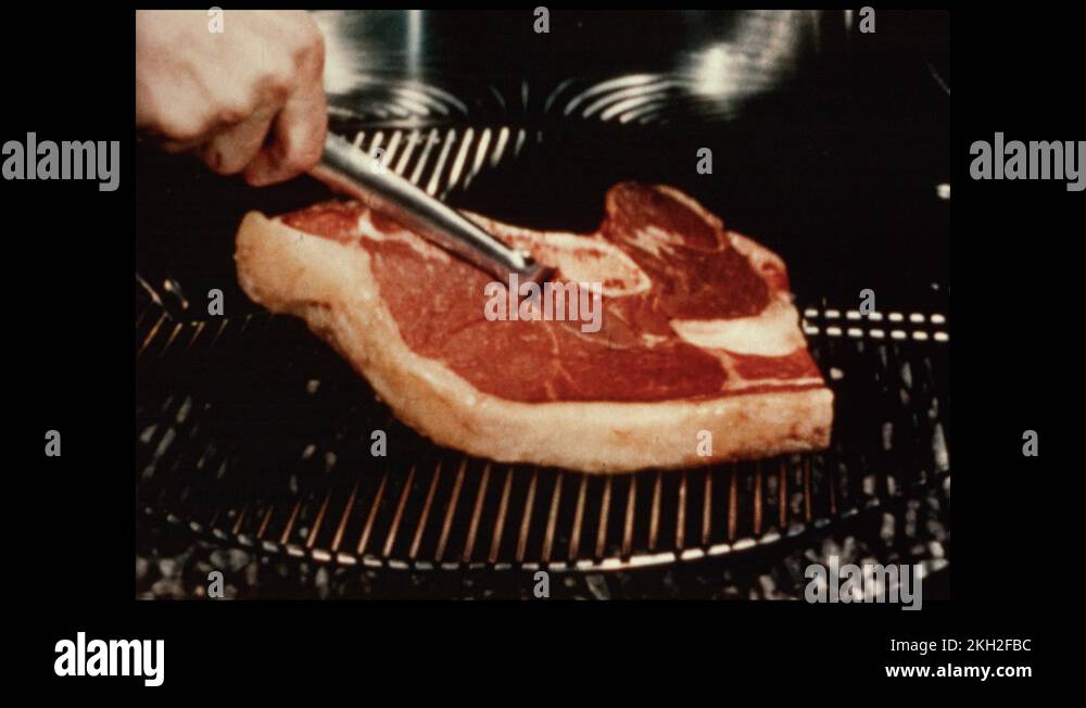 1950s Man flips over steak on grill. Man moves steak to plate Stock