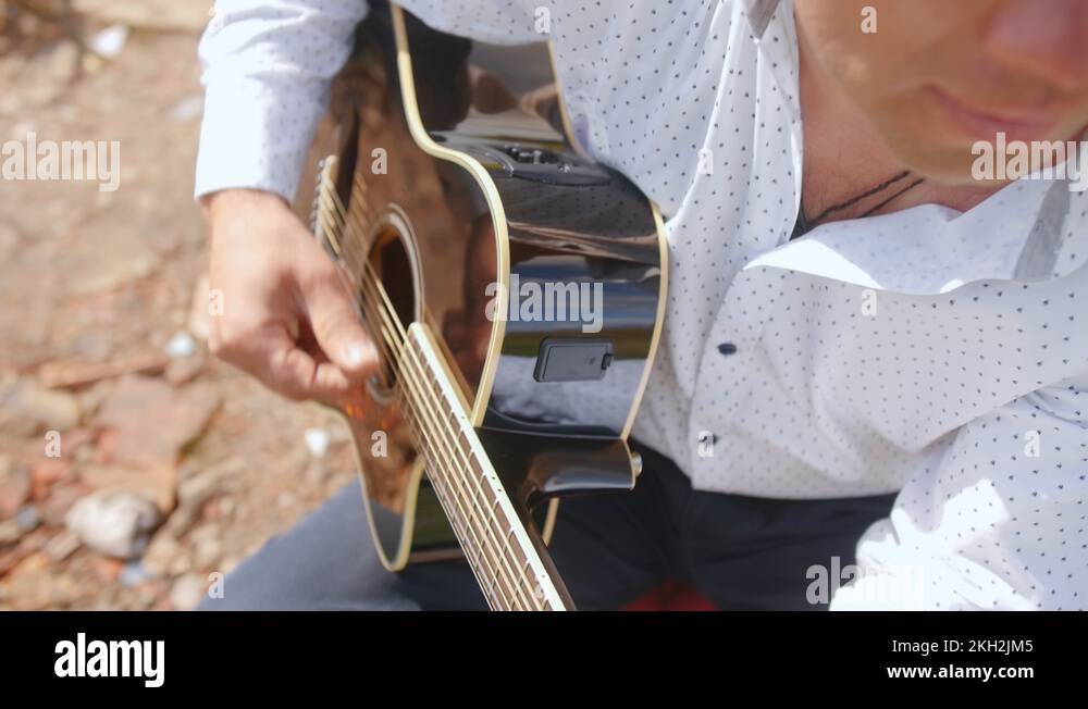 Man plays guitar and sings on nature. Guitarist touching guitar strings