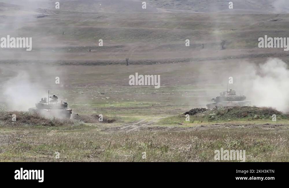 Two battle tanks fire cannons and reverse into military berm at range