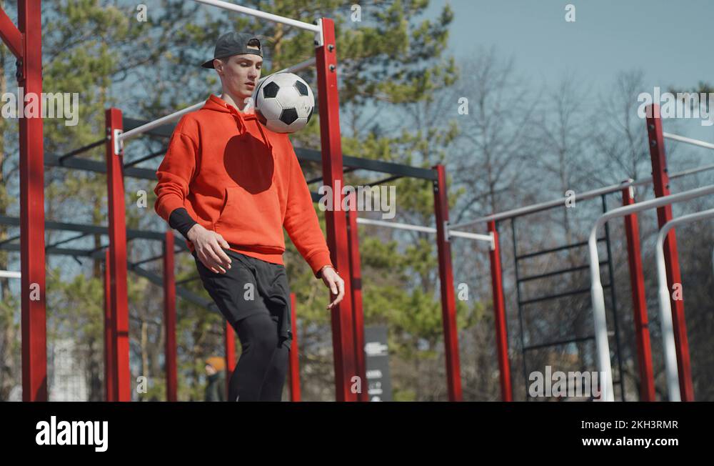 A young guy throws a soccer ball his feet. Street football. Slow motion