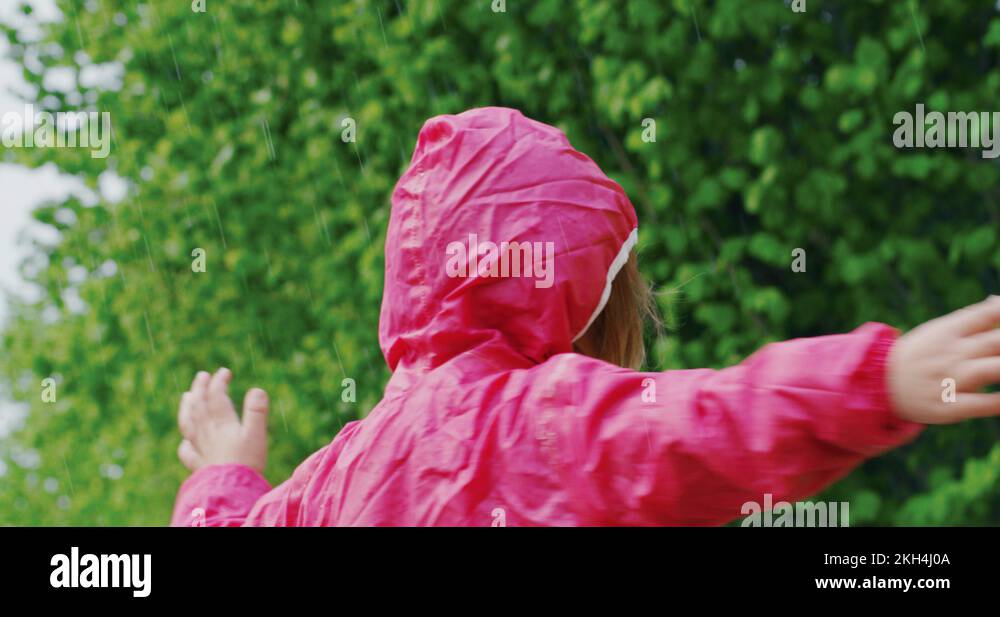 Authentic shot of cute happy little girl in raincoat is enjoying the rain Stock Video Footage