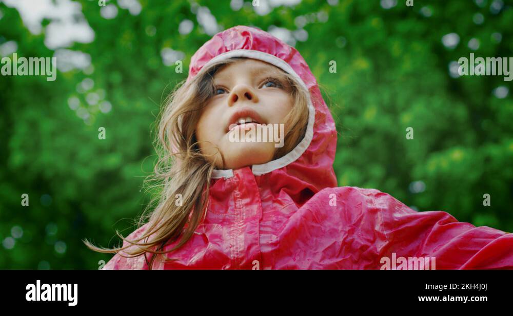 Authentic shot of cute happy little girl in raincoat is enjoying the rain Stock Video Footage