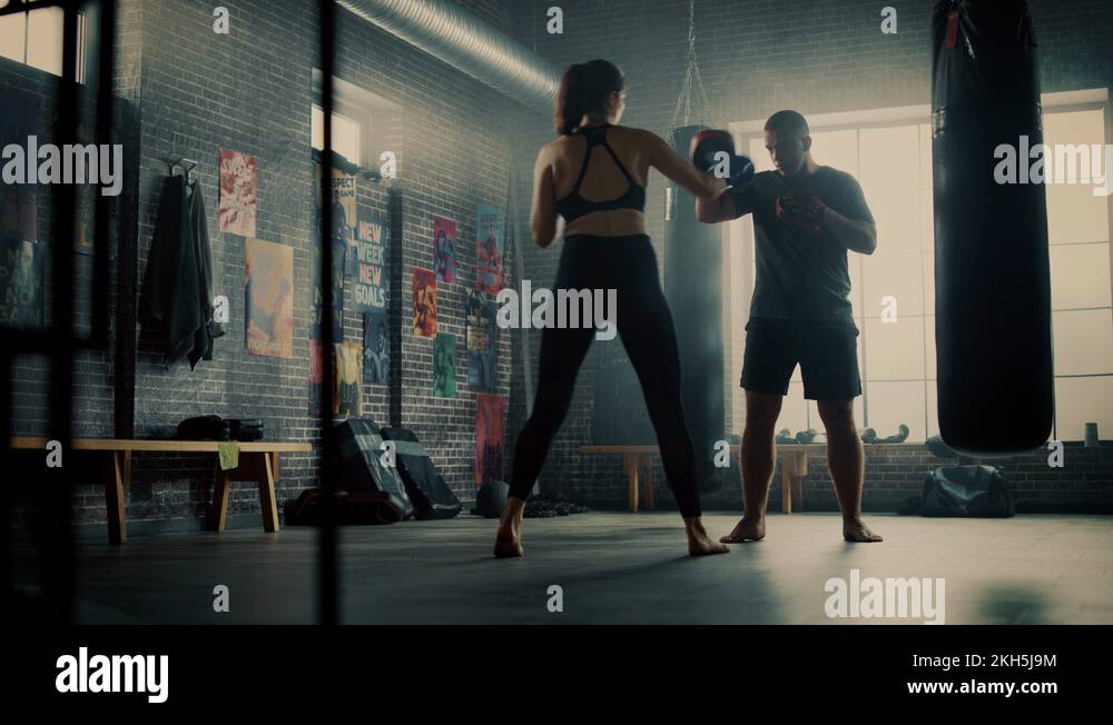 Fit Athletic Woman Kickboxer Punches and Hits the Punching Pads During