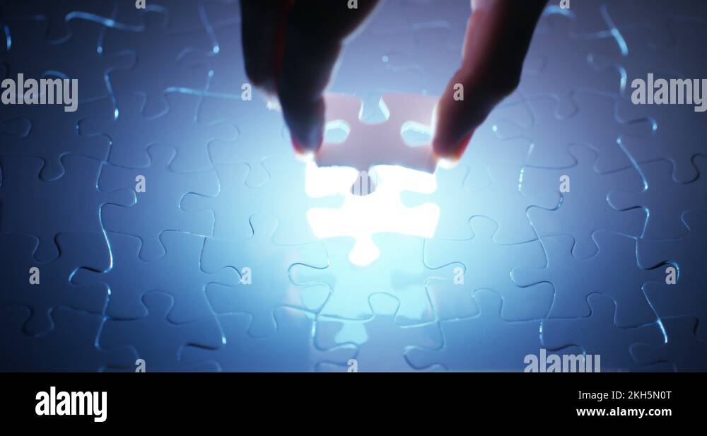 Close up of a hand completes a puzzle by putting the last missing piece