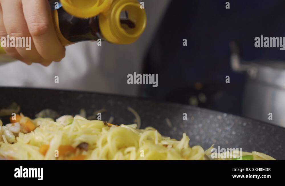 Lady pouring fish sauce on StirFried Vegetables With Rice Noodles on a