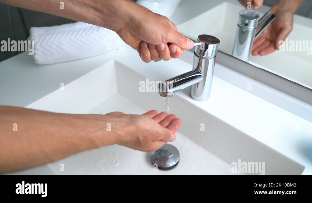 Man washing hands in bathroom sink at home checking temperature with hand Stock Video Footage
