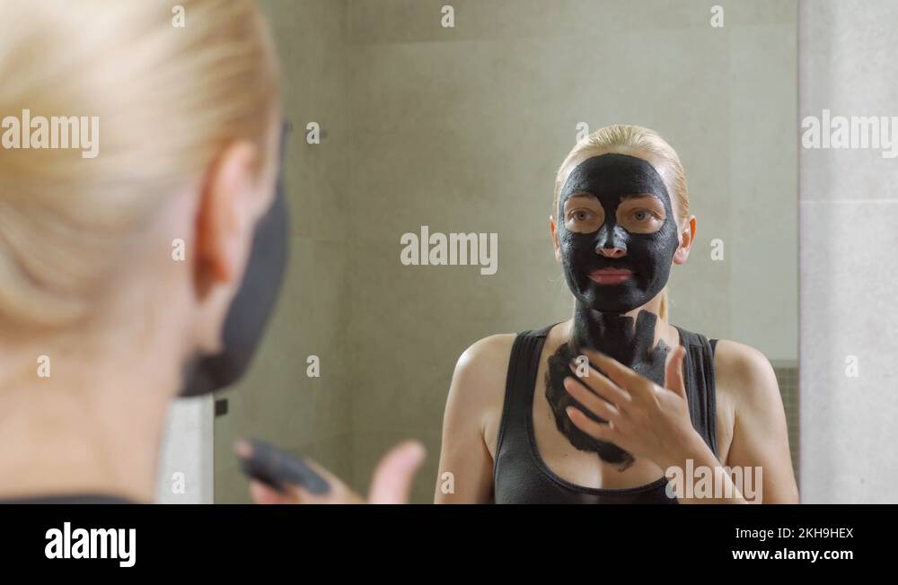 The woman puts a mud mask on a face. Face care. Mud Spa procedures. Day