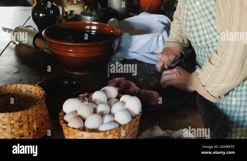 A woman in traditional dress prepares food, cuts meat with a knife