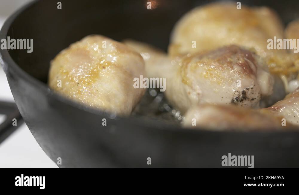 Making pan fried chicken drumsticks in cast iron frying skillet Stock