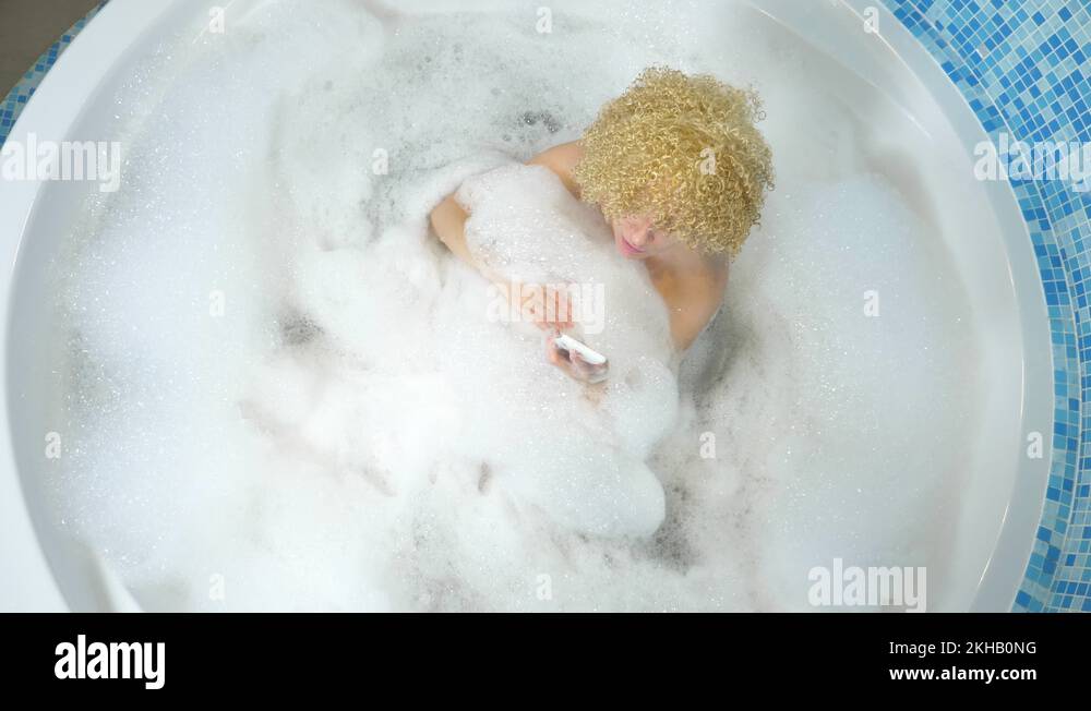 Cute blonde girl in the bathtub with foam dropped the phone into the water. and Stock Video