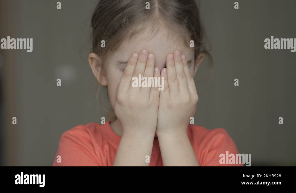 Cute little girl open her face with hands. Girl looks and is surprised ...