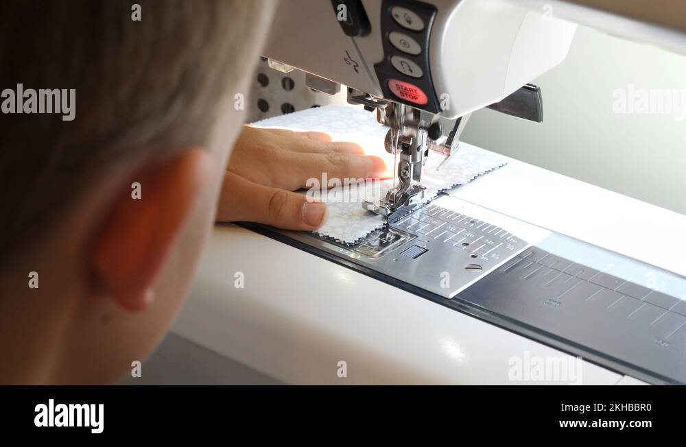 Young boy uses a sewing machine to make a quilt in his home Stock Video