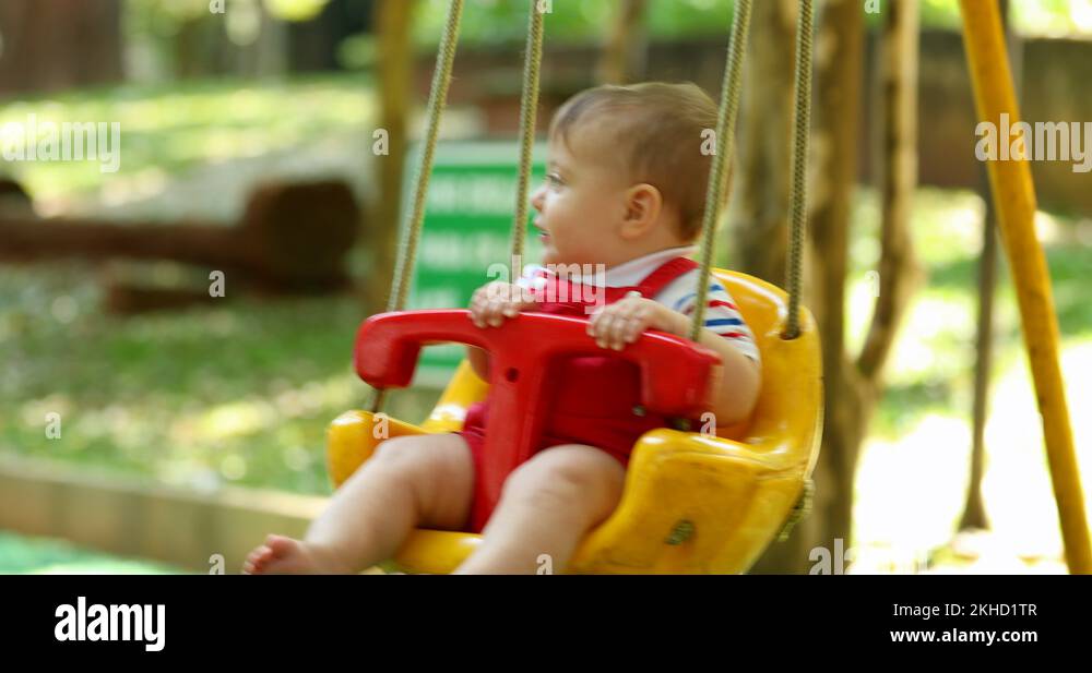 Joyful baby boy toddler at playground swing at park Stock Video Footage