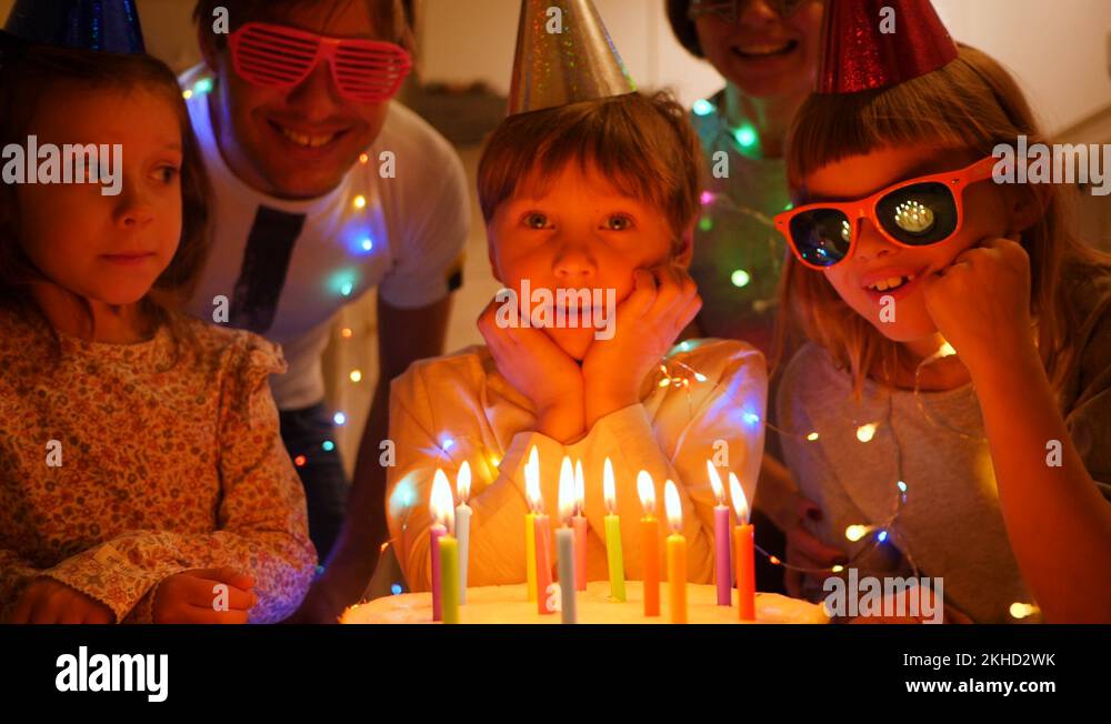Cute kid boy blow out candles on birthday cake slow motion with his