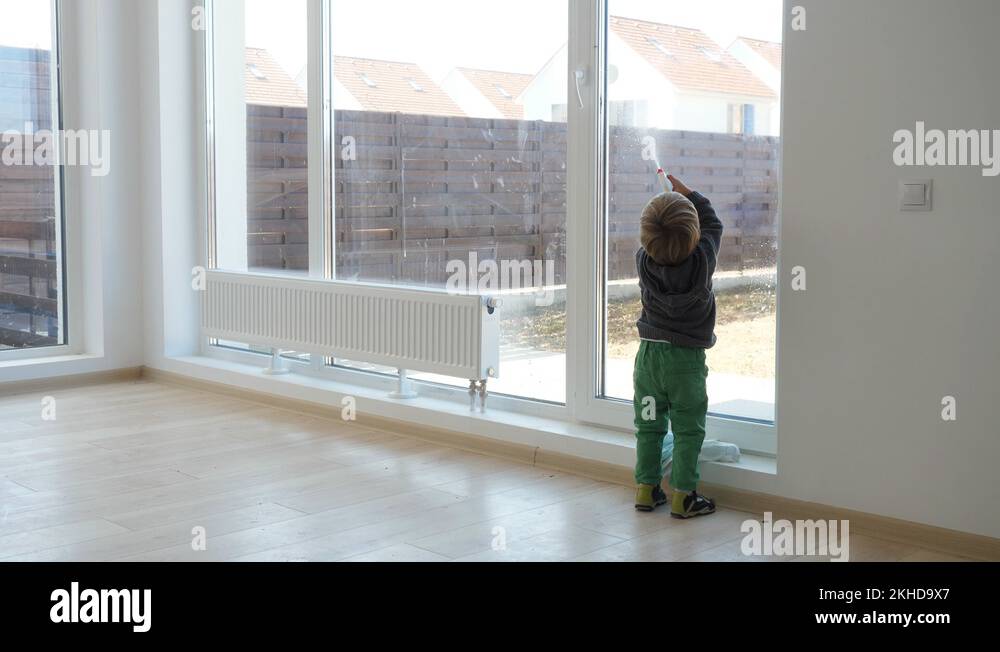 Funny and hardworking little child cleaning window, kid use chemicals ...