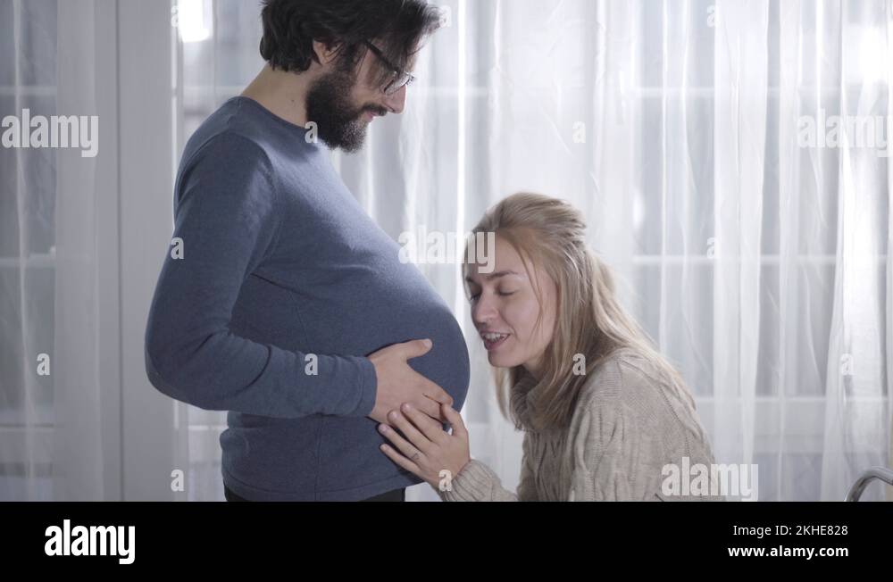 laughing-caucasian-girl-putting-ear-to-husband-s-pregnant-belly