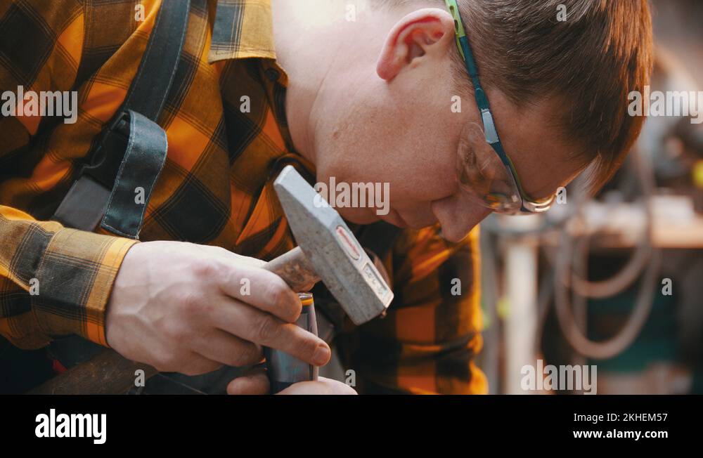 Carpentry a man woodworker making notches with a chisel and a hammer