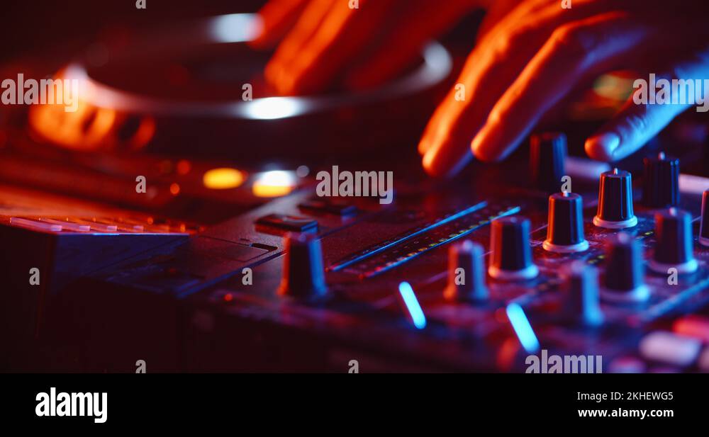 Disc jockey working on his professional mixer controller, sliding the