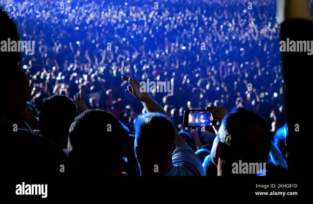 Crowd of fans standing in fan zone during rock or pop music concert. 4K