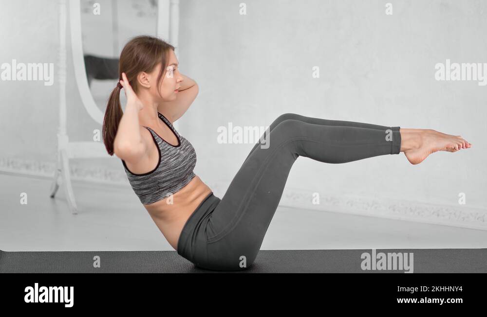 Endurance young fitness girl breathing during abs workout turning body