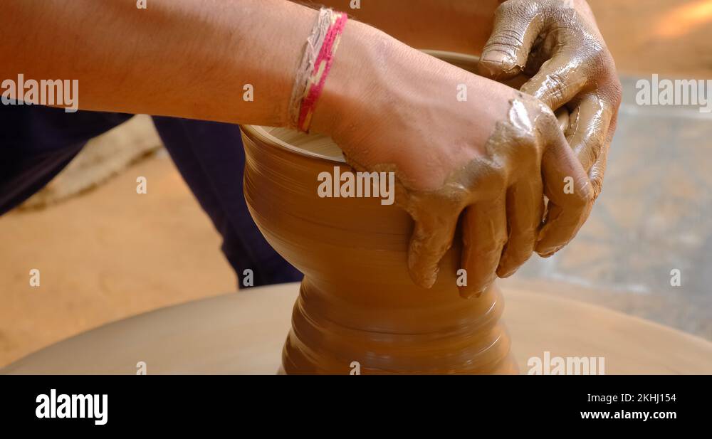 Skilled hands of potter shaping the clay on potter wheel and sculpting ...