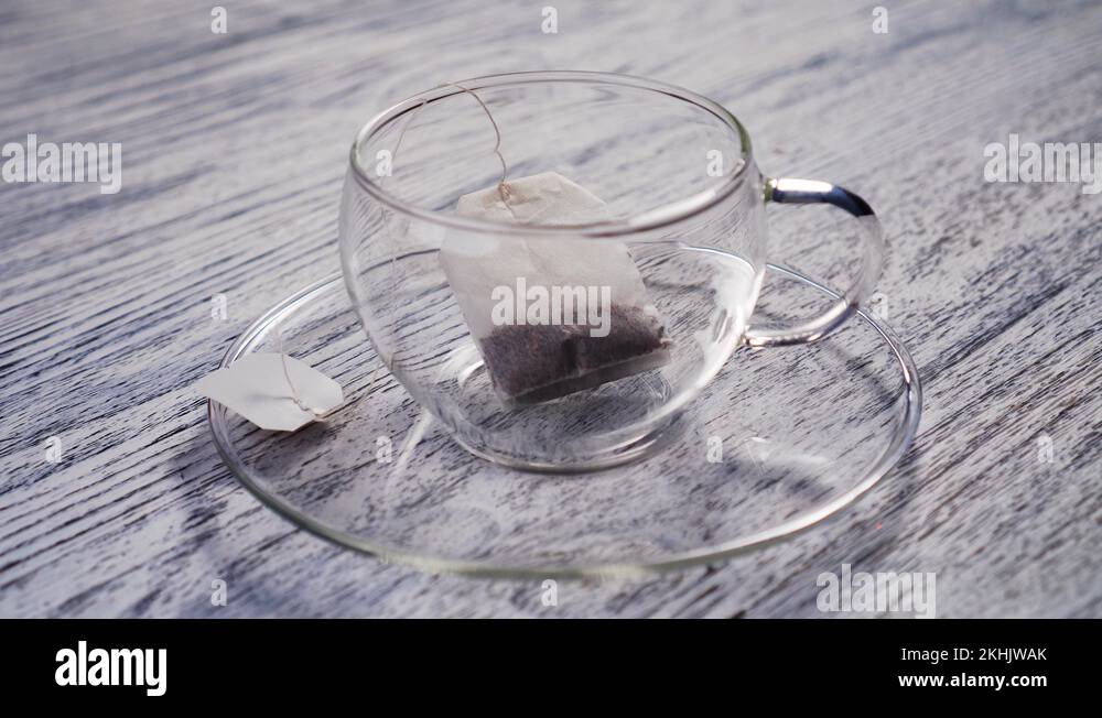 Boiling water is poured into a glass transparent cup with a bag of black arom Stock Video